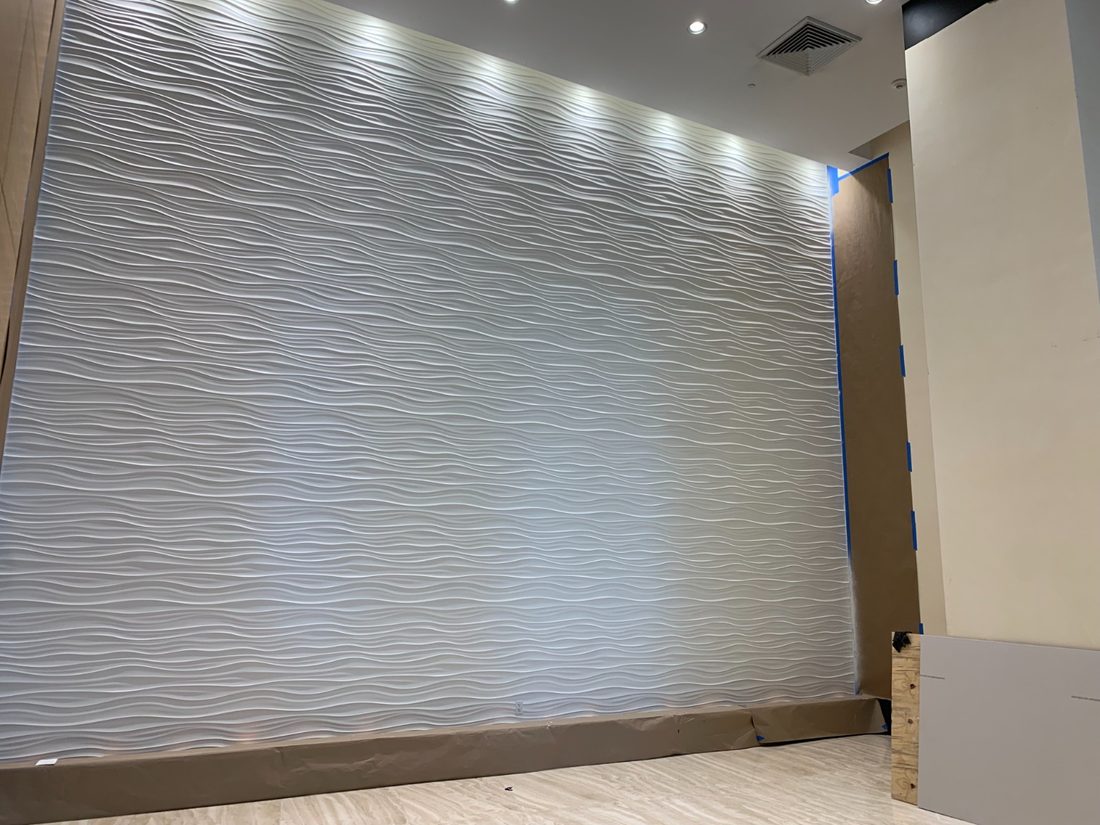 Sculpted wave wall panelling picked out by grazing light